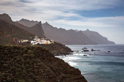 Scenic view of sea and mountains against cloudy sky