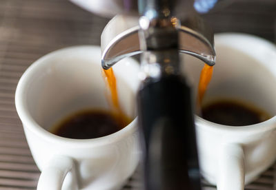 Coffee pouring in cups from espresso maker