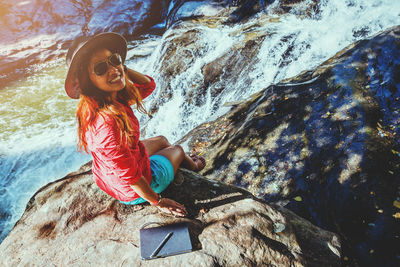 Portrait of smiling woman sitting on rock