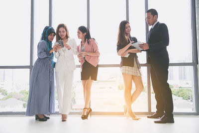 Colleagues discussing while standing by window in office