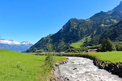 Scenic view of landscape and mountains against blue sky