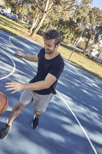 Full length of man playing on basketball court