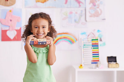 Portrait of girl holding toy block at home