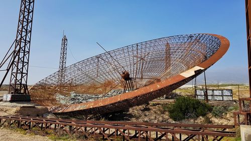 Rusty metallic parabolic antenna against clear blue sky