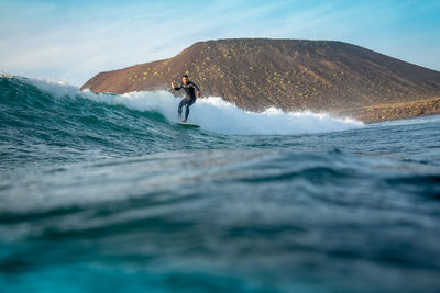 Man surfing in sea against sky