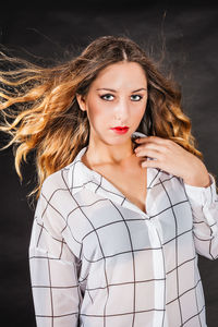 Portrait of young woman against black background