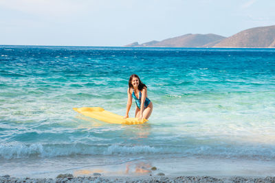 Rear view of woman swimming in sea against sky