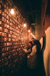 Man and woman standing against illuminated wall