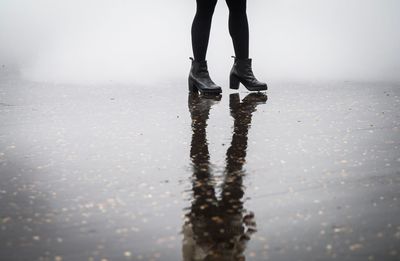 Low section of woman walking on wet street