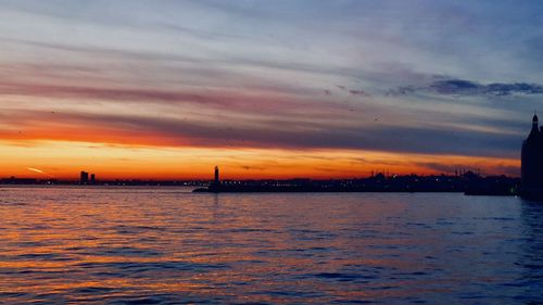 Scenic view of sea against dramatic sky during sunset