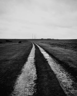 Road leading towards field against sky