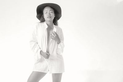 Young woman looking away while standing against white background