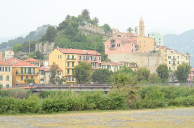 Houses by buildings in town against sky