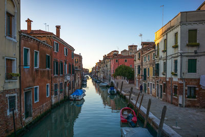 Canal amidst buildings in city against clear sky