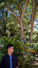 Portrait of man standing against tree trunk