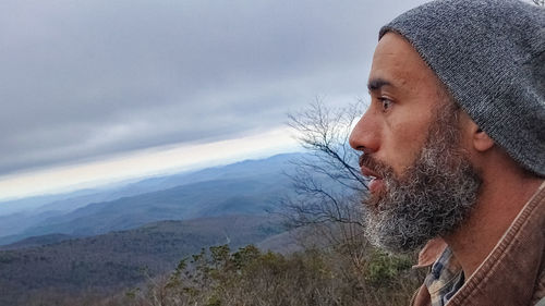 Portrait of young man looking away against sky