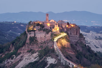 Illuminated fort on mountain against sky at dusk