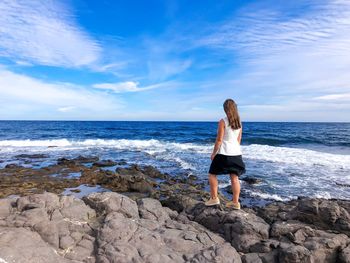 Full length of man on rock at beach against sky