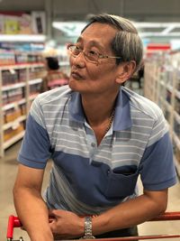 Mid adult man looking away while standing at store