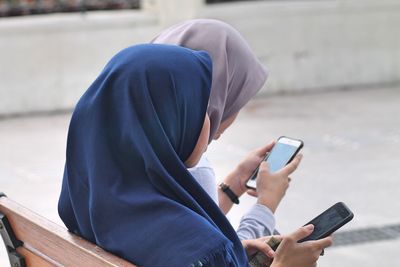 Young women using phones while sitting on bench