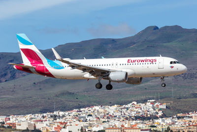 Airplane flying over mountains against sky