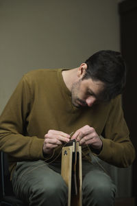 Young man working while sitting against wall