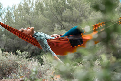 Portrait of man relaxing on hammock in forest