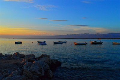 Boats in calm sea at sunset