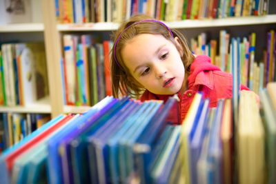 Girl selecting book while standing in library