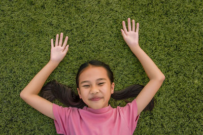 Portrait of happy girl lying on grassy field