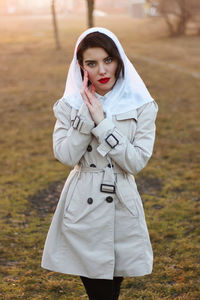 Portrait of beautiful young woman standing on field