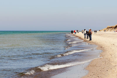 People at beach against sky on sunny day