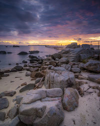 Rocks on beach against sky during sunset