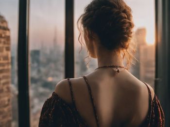 Rear view of woman looking through window