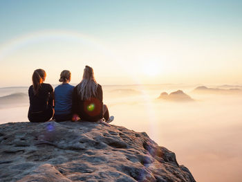 Kleiner winterberg. girl friends sitting together on cliff. amazing misty morning and daybreak show