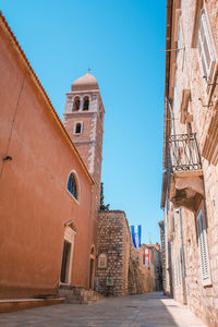 Alley amidst buildings against blue sky