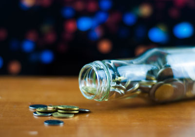 Close-up of glass bottle with coins on table