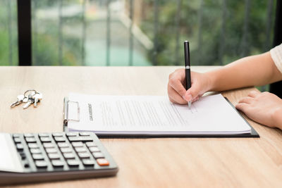 Midsection of person reading book on table