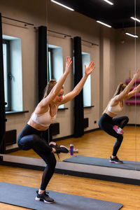 Young woman in sportswear doing stretching in indoor gym