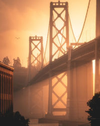 Bridge over river in city during sunset