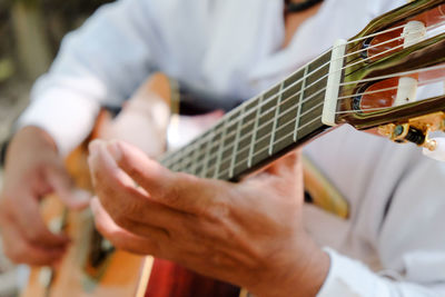 Midsection of man playing guitar