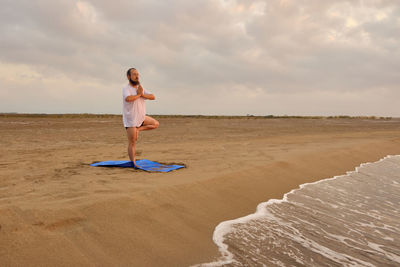 Woman standing on beach against sky