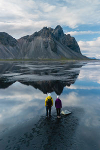 Rear view of man standing on lake against sky