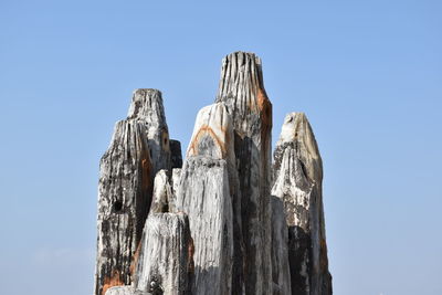 High section of wooden post against clear sky on sunny day