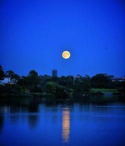 Hot air balloon flying over water against clear blue sky