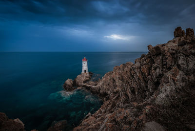 Lighthouse by sea against sky