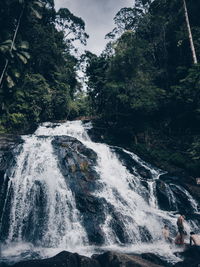 Scenic view of waterfall in forest against sky