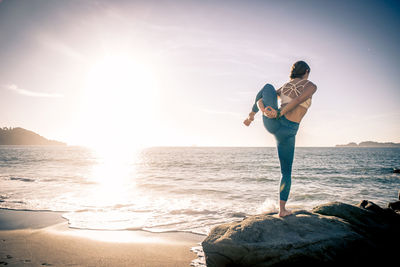 Full length of man standing on rock at beach against sky