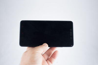 Close-up of hand holding smart phone against white background