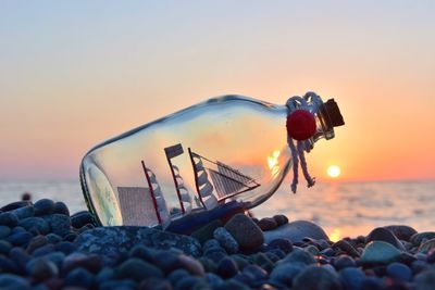 Pebbles on beach against sky during sunset